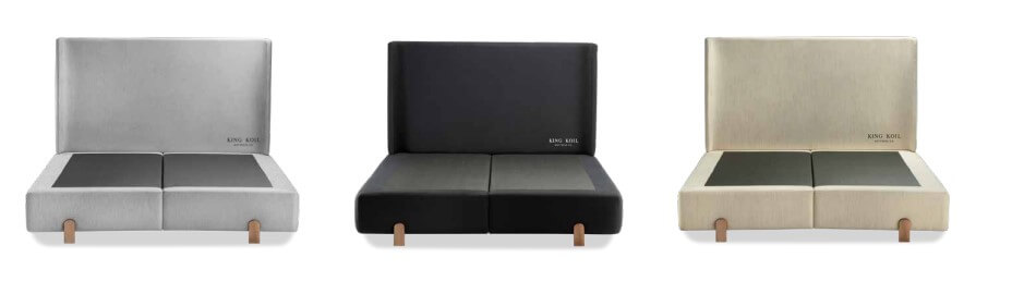 Mosaico exibindo três opções de cores para a Cama Elegance com base Box Baú: cinza claro, grafite e bege. Todas apresentam cabeceira estofada com abas laterais e pés de madeira natural.