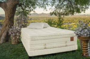 Colchão de luxo King Koil modelo Pacific posicionado em um cenário externo com vista panorâmica para a natureza. A imagem destaca a altura do colchão, o acabamento artesanal e as camadas de conforto premium, sendo a escolha perfeita ao comprar colchão de luxo King Koil de alto padrão.